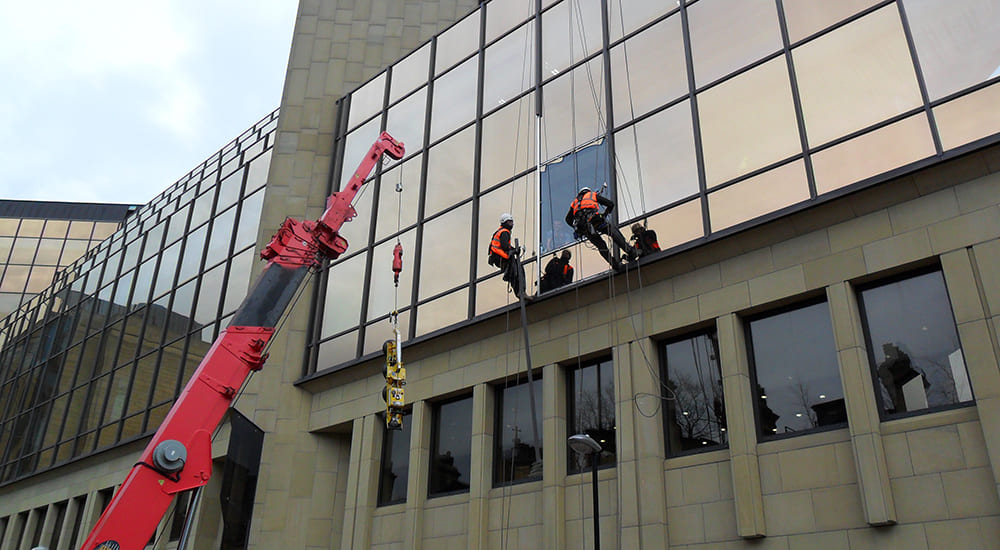 Rope access glazing specialists carrying out high-level façade glass replacement on a commercial building